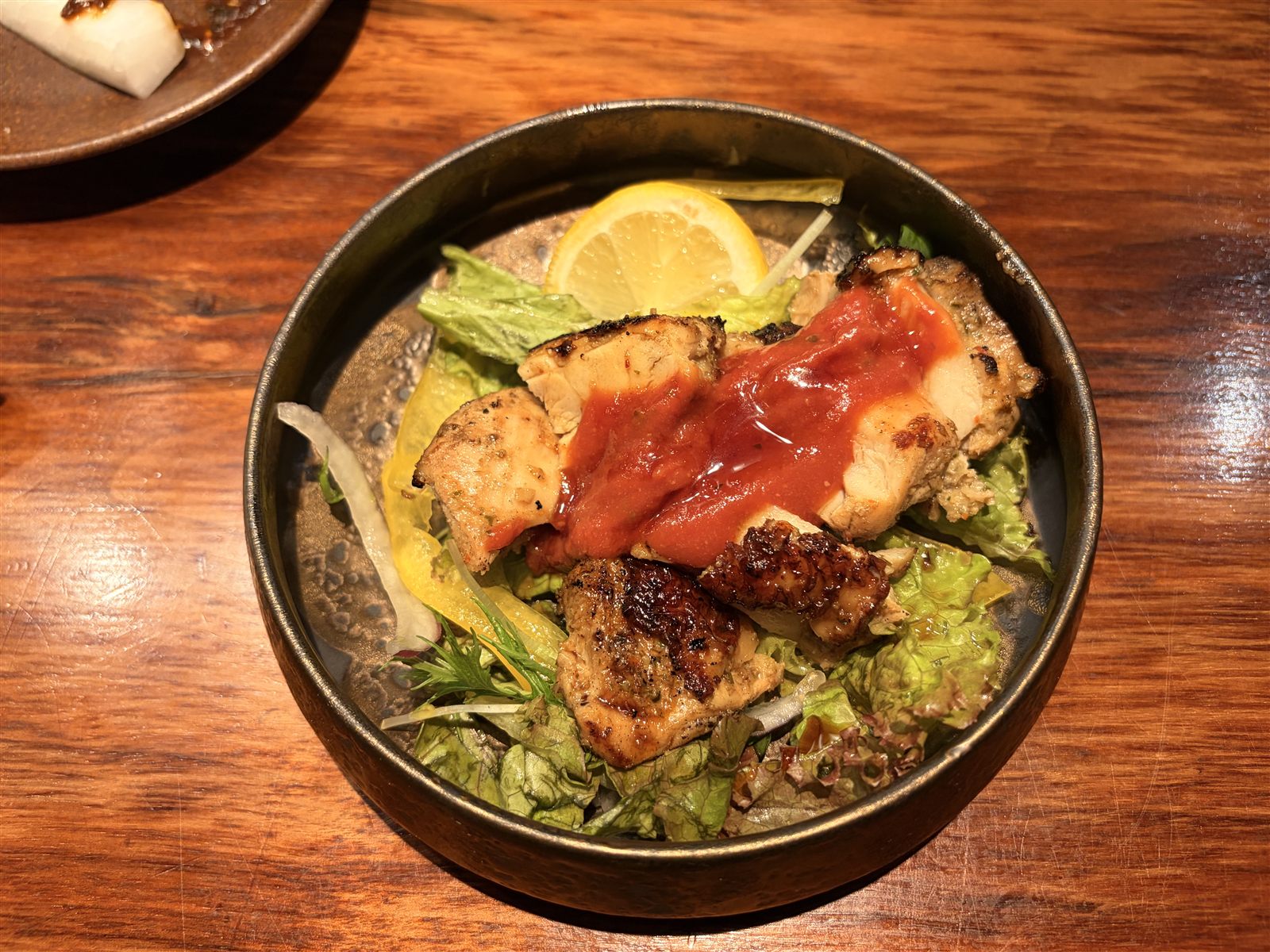 満月堂の鯛料理。焼いた身がサラダの上にのり、赤いソースとレモンが添えられている