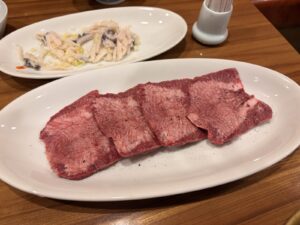 焼肉海雲亭の厚切りの黒タン。黒こしょうがふられた分厚いタンが4枚、奥にせんまい刺し